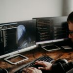 un homme assis à un bureau avec plusieurs écrans d'ordinateur